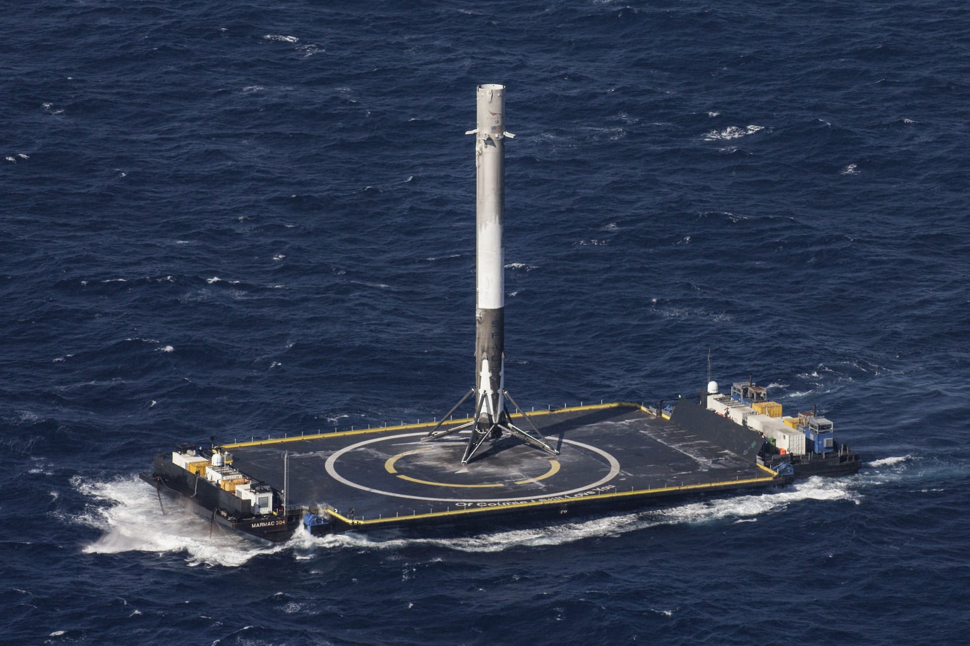 A Falcon 9 first stage standing on the deck of the drone ship Of Course I Still Love You at sea.